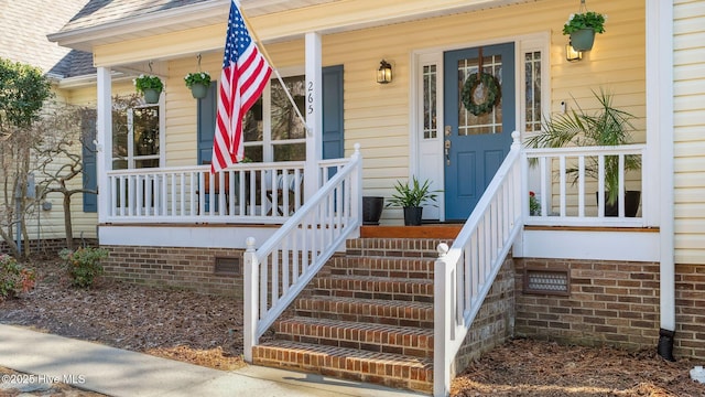 entrance to property with roof with shingles, a porch, and crawl space