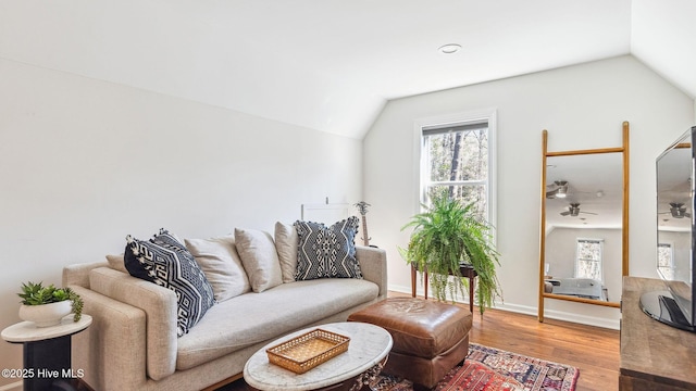 living area featuring lofted ceiling, wood finished floors, and baseboards