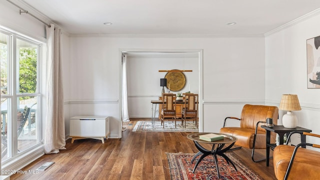 living area featuring ornamental molding, visible vents, and wood finished floors