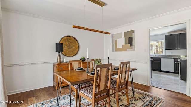 dining room featuring baseboards, crown molding, and light wood finished floors