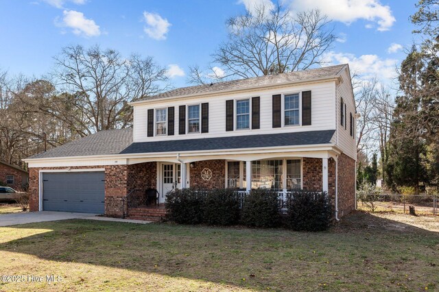 traditional-style house with concrete driveway, brick siding, a front lawn, and an attached garage