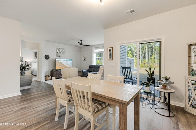 dining room featuring a ceiling fan, wood finished floors, visible vents, and baseboards