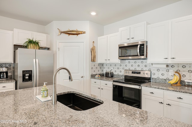 kitchen with white cabinets, backsplash, stainless steel appliances, and a sink