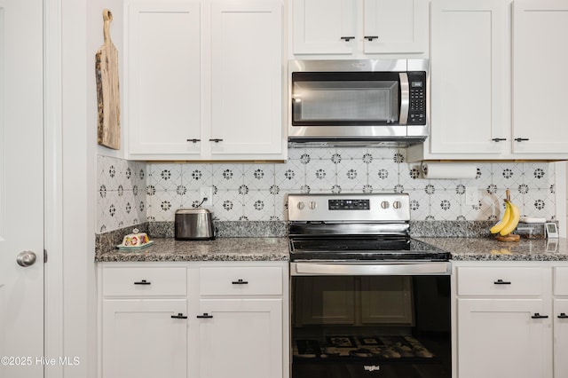 kitchen with tasteful backsplash, appliances with stainless steel finishes, white cabinets, and dark stone countertops