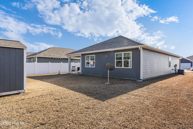 rear view of house featuring a storage shed, an outdoor structure, and fence