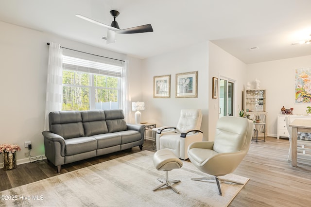 living room with ceiling fan, baseboards, and wood finished floors