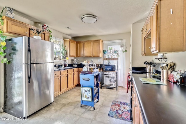 kitchen with dark countertops, visible vents, appliances with stainless steel finishes, and a sink