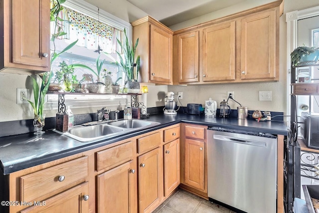 kitchen featuring dark countertops, a sink, stainless steel dishwasher, and light tile patterned floors