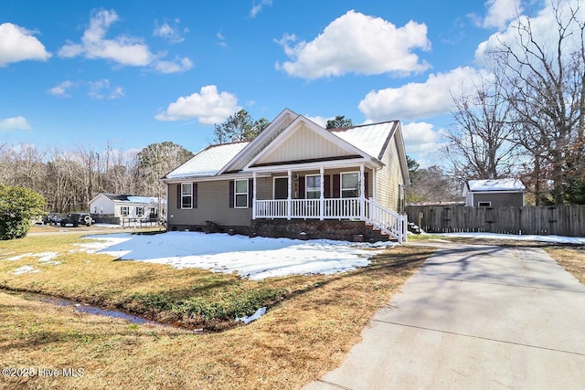 view of front of home with a front lawn, fence, a porch, and board and batten siding