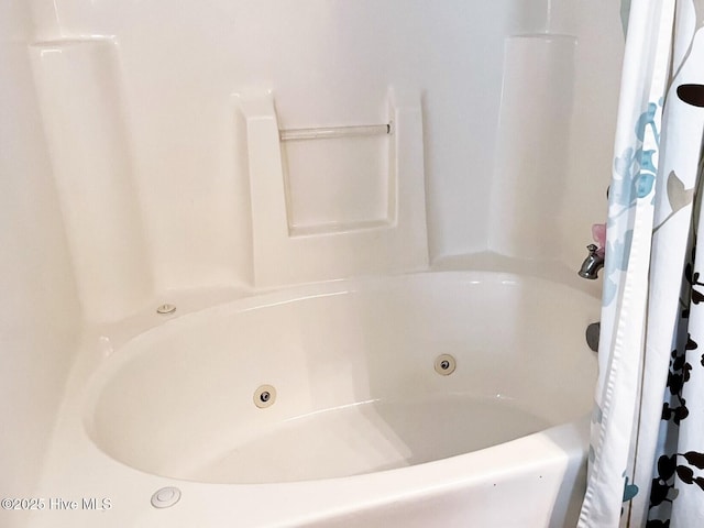 bathroom featuring curtained shower and a jetted tub