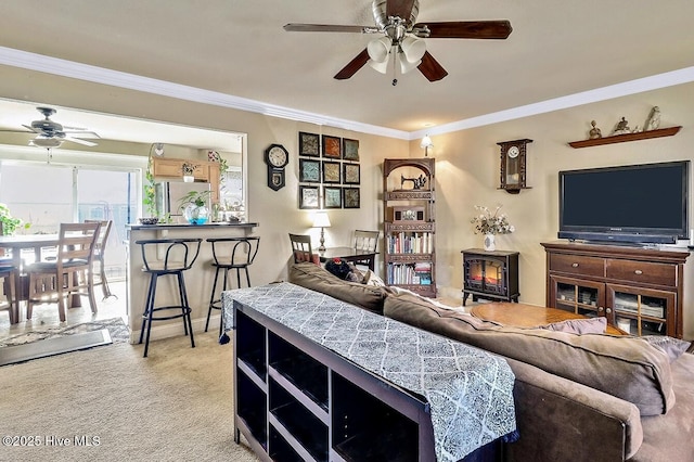 living room with a wood stove, ceiling fan, light carpet, and ornamental molding