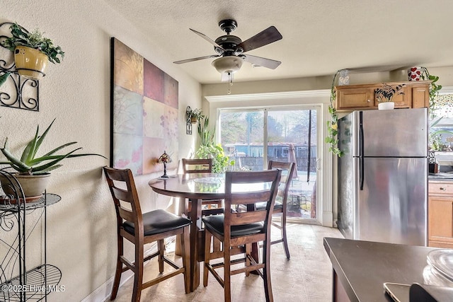 dining room with ceiling fan, a textured wall, and a textured ceiling