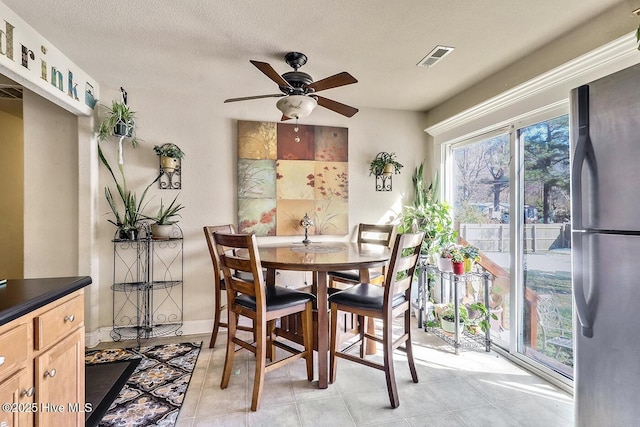 dining space with ceiling fan, visible vents, and a textured ceiling