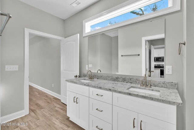 147 NE 18th St, Oak Island, NC 28465 - bathroom with a shower, wood finished floors, double vanity, baseboards, and a walk in closet
