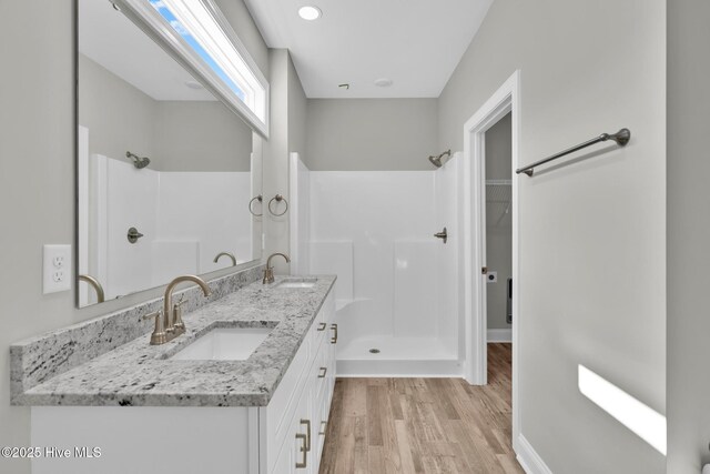 147 NE 18th St, Oak Island, NC 28465 - full bathroom with double vanity, wood finished floors, toilet, baseboards, and a walk in closet