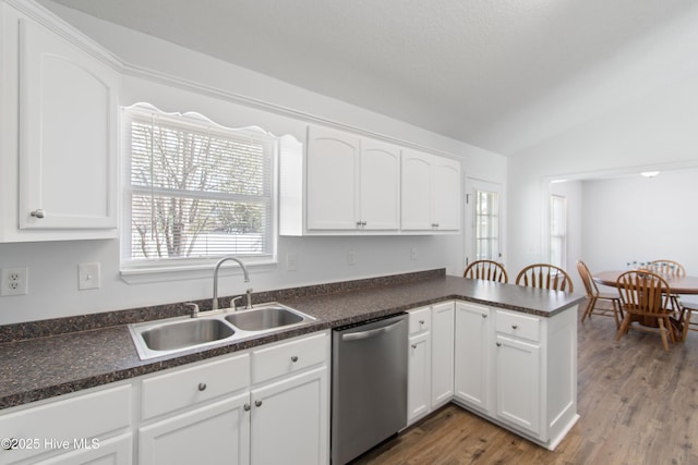 kitchen with stainless steel dishwasher, vaulted ceiling, white cabinets, and a sink