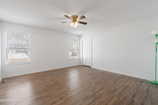 empty room with dark wood-type flooring, a ceiling fan, baseboards, and a textured ceiling