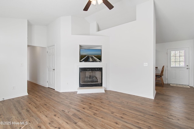 unfurnished living room with wood finished floors, a fireplace with raised hearth, and baseboards