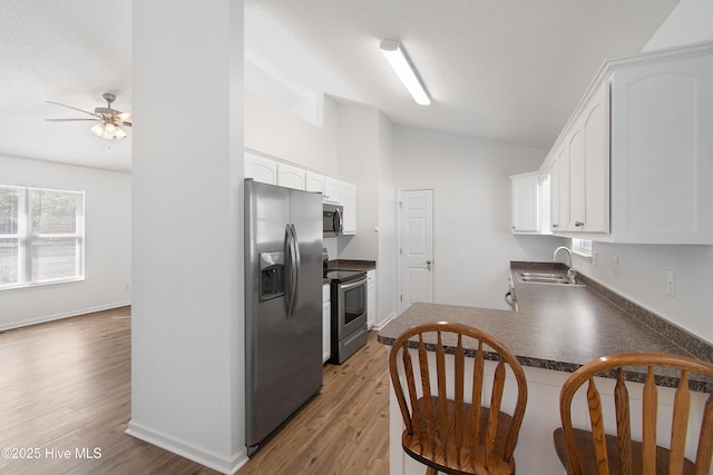 kitchen featuring dark countertops, appliances with stainless steel finishes, white cabinetry, and a sink