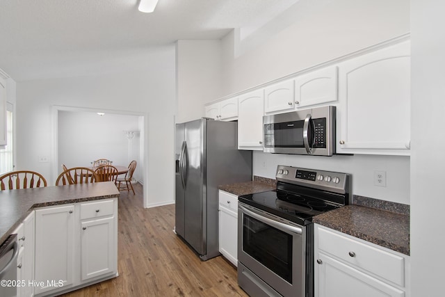 kitchen featuring dark countertops, white cabinets, light wood finished floors, and stainless steel appliances