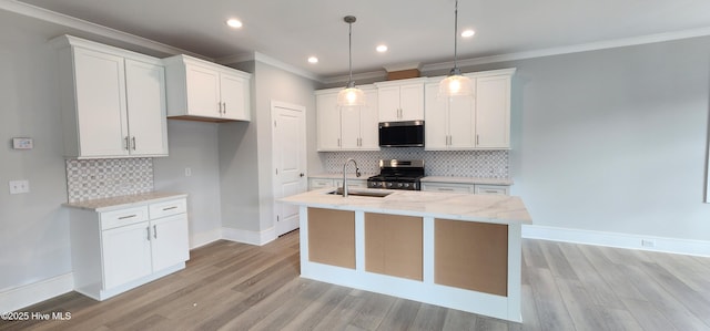 kitchen with appliances with stainless steel finishes, white cabinetry, a sink, and an island with sink