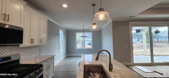 kitchen with light stone counters, gas stove, crown molding, and decorative backsplash