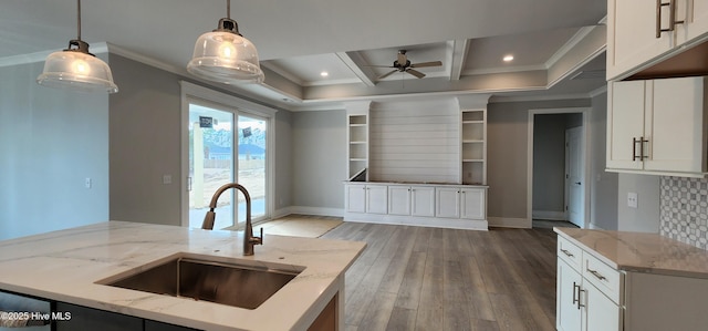 kitchen with crown molding, hanging light fixtures, a sink, wood finished floors, and coffered ceiling