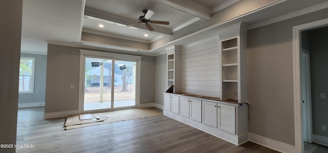 interior space featuring ornamental molding, wood finished floors, beam ceiling, and baseboards