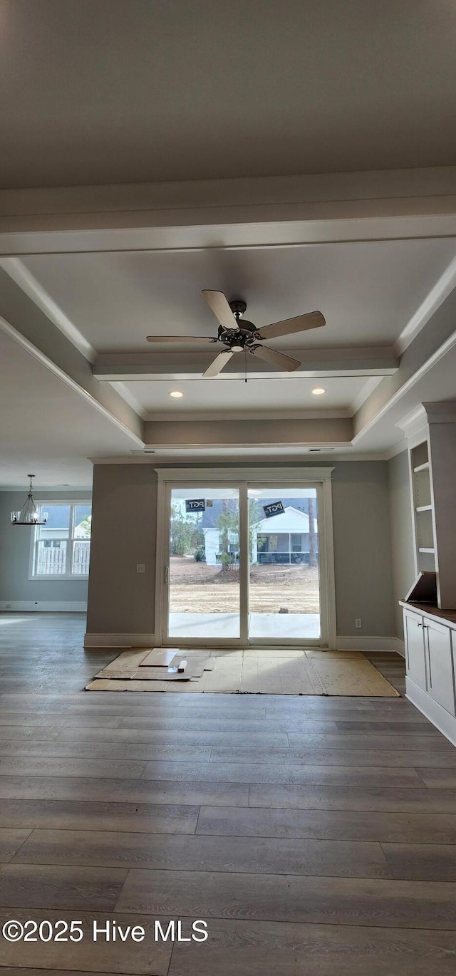 unfurnished living room with ceiling fan with notable chandelier, baseboards, wood finished floors, and ornamental molding