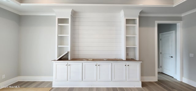 interior space with ornamental molding, wood finished floors, and baseboards