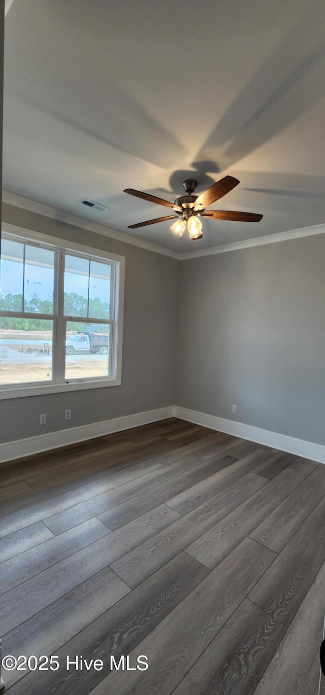 unfurnished room featuring baseboards, visible vents, ornamental molding, and dark wood finished floors