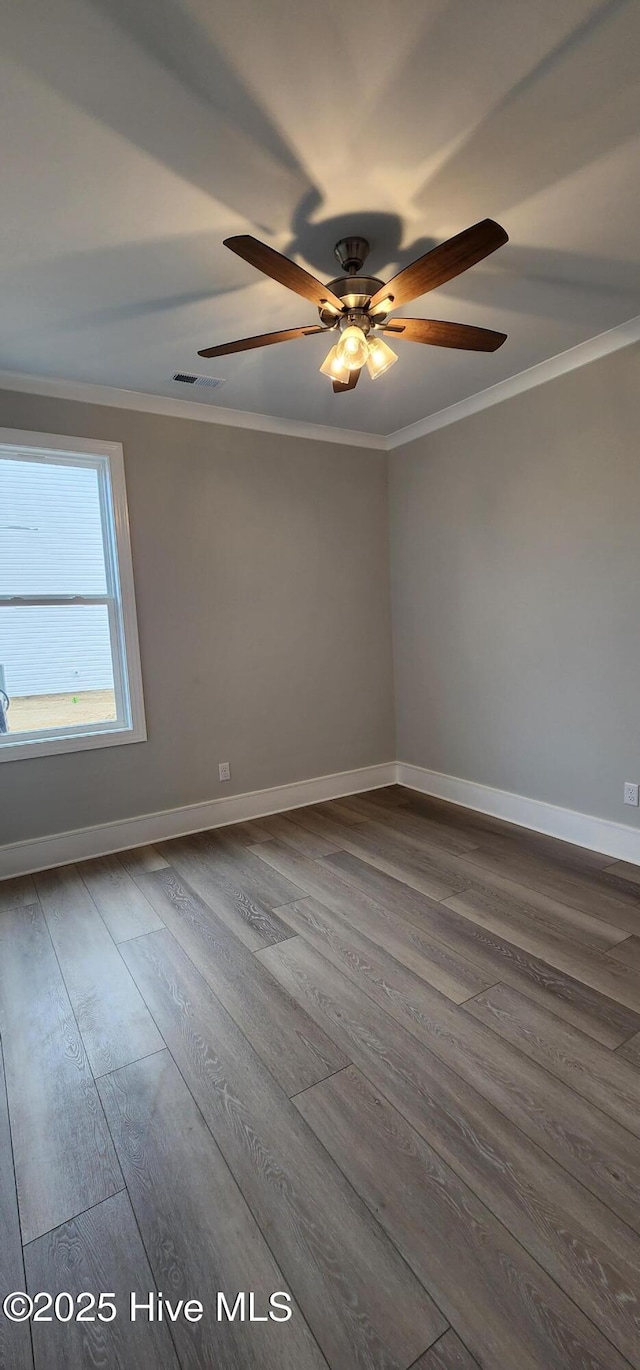 unfurnished room featuring baseboards, visible vents, ornamental molding, and wood finished floors