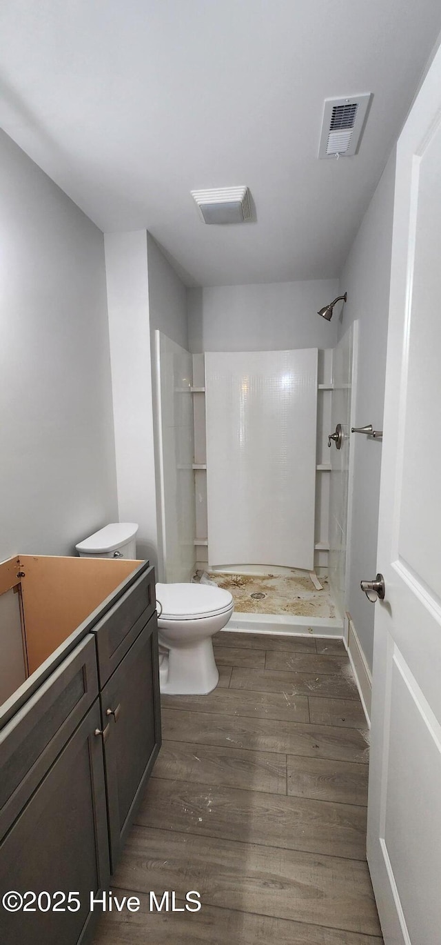 bathroom with visible vents, a shower stall, toilet, and wood finished floors