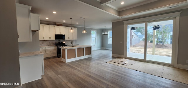 kitchen featuring tasteful backsplash, an island with sink, appliances with stainless steel finishes, ornamental molding, and wood finished floors