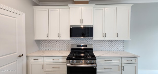 kitchen with tasteful backsplash, gas stove, white cabinetry, and light stone countertops