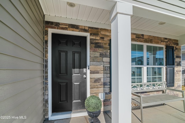 entrance to property featuring covered porch and stone siding