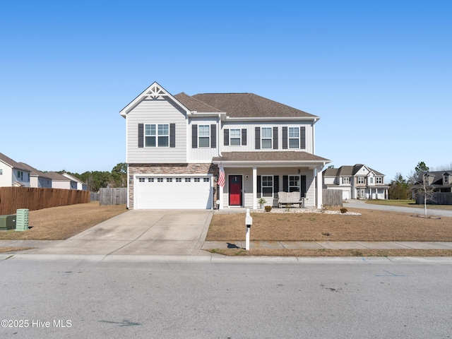 view of front of home featuring driveway, stone siding, an attached garage, covered porch, and fence