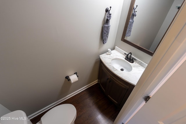 half bath with wood finished floors, vanity, toilet, and baseboards