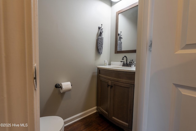 bathroom featuring baseboards, vanity, toilet, and wood finished floors