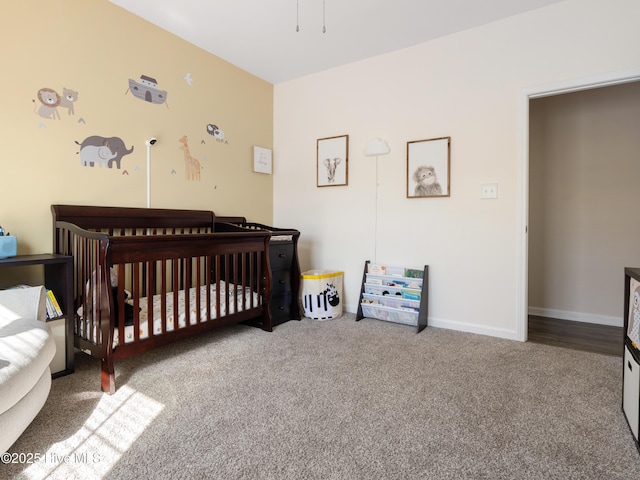 carpeted bedroom featuring a crib and baseboards