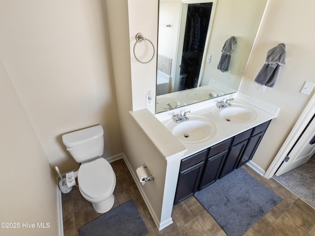 full bathroom featuring toilet, double vanity, and a sink