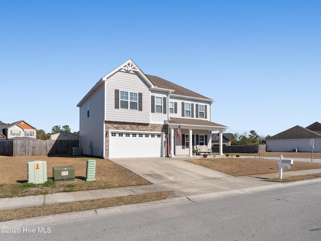 view of front of property with a garage, stone siding, fence, and driveway