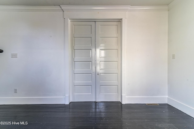 spare room featuring baseboards, wood finished floors, and crown molding