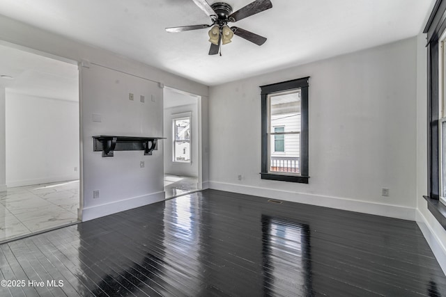 unfurnished living room featuring wood finished floors, a wealth of natural light, and baseboards