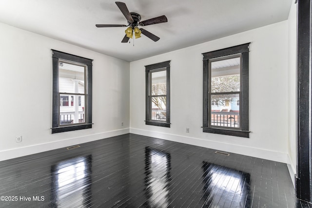 empty room with dark wood-style floors, visible vents, baseboards, and ceiling fan