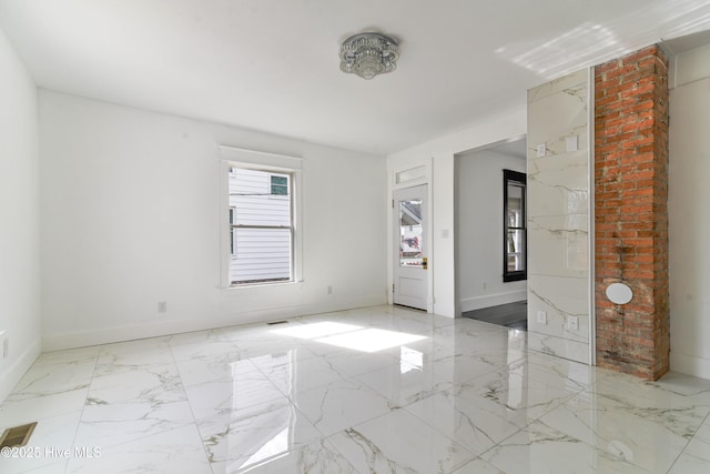 empty room featuring marble finish floor, visible vents, and baseboards