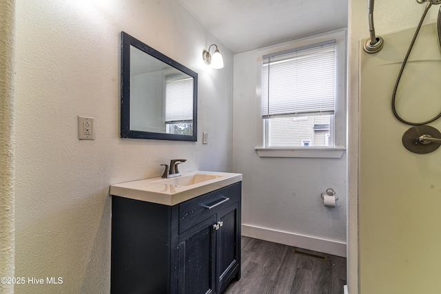 bathroom with visible vents, baseboards, wood finished floors, and vanity