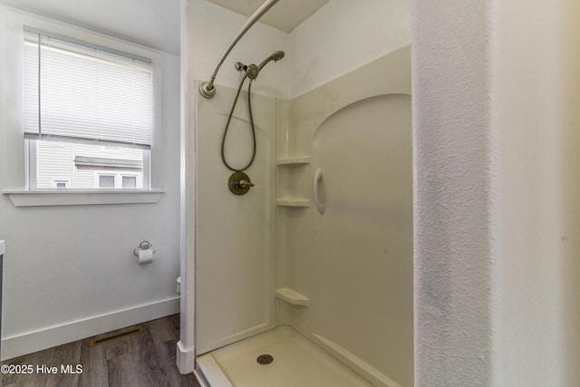 bathroom with a stall shower, baseboards, visible vents, and wood finished floors