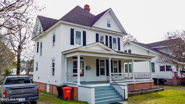 view of front of property with covered porch, roof with shingles, and a chimney