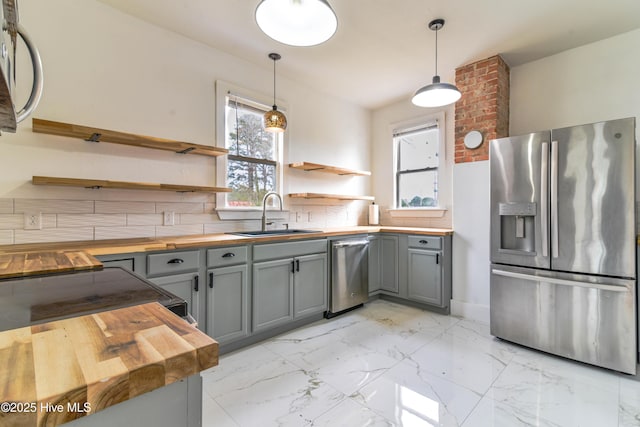 kitchen featuring stainless steel fridge with ice dispenser, wood counters, marble finish floor, open shelves, and a sink